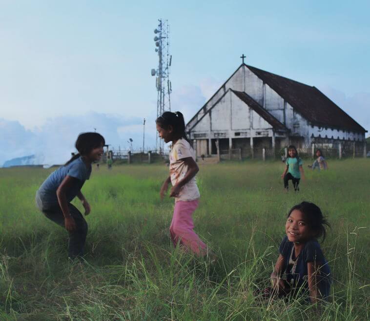 The kids playing in the fields with view of Baptist Church