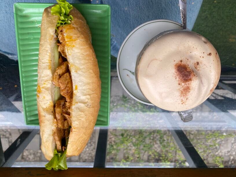 Grabbing a Banh Mi for breakfast with coconut coffee in Hanoi Train Street